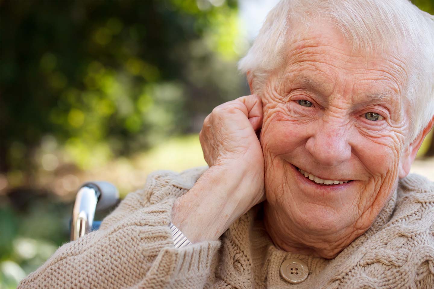 Photo of a smiling man wearing a cable knit cardigan outdoors