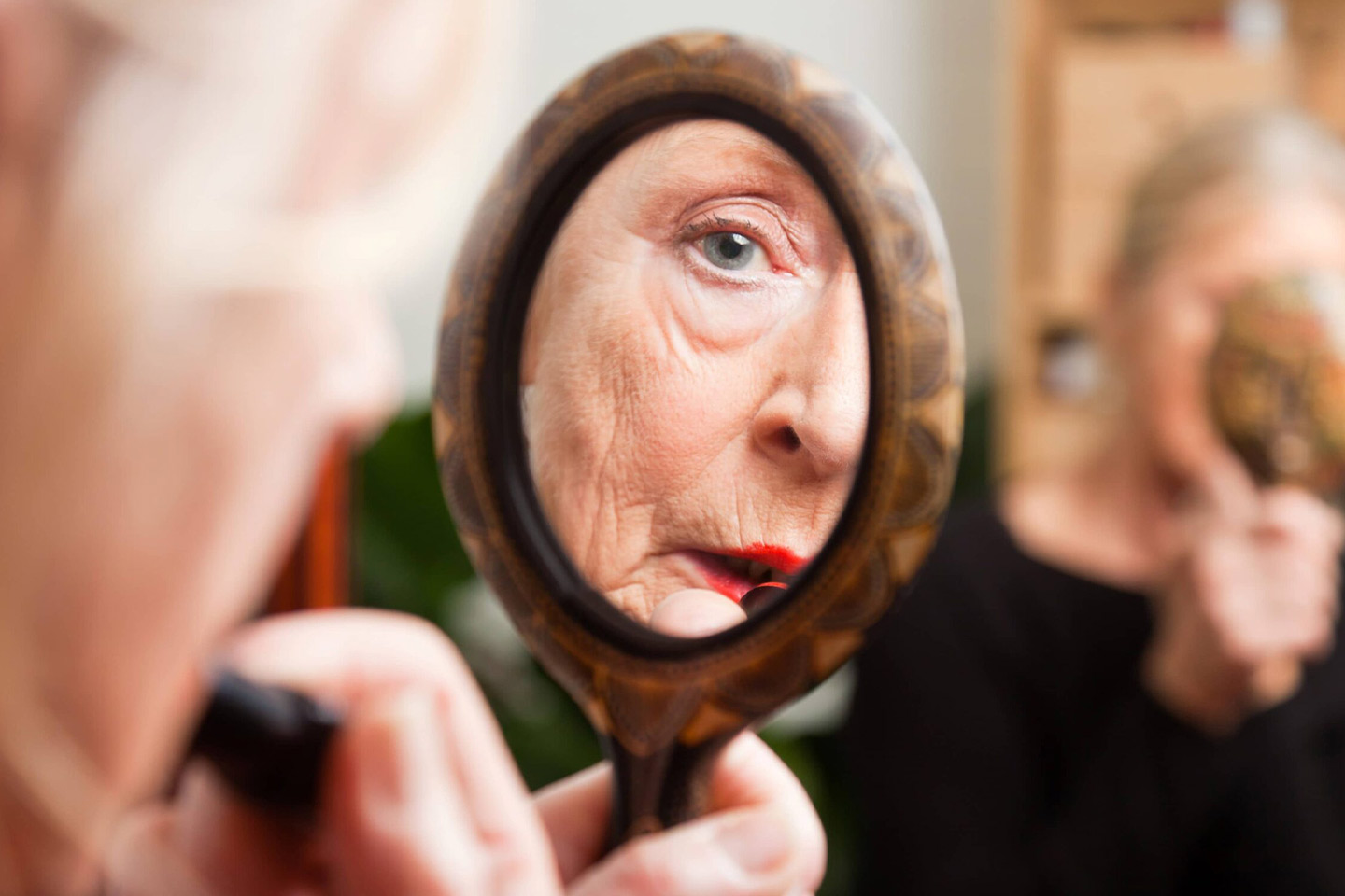 Photo of a woman putting on lipstick