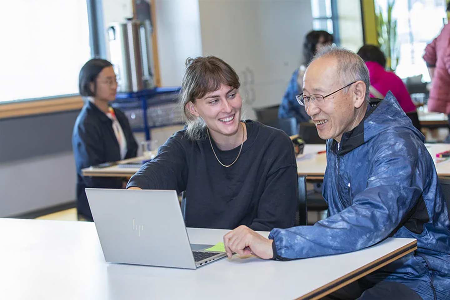 Photo of two people sitting at a laptop in a classroom