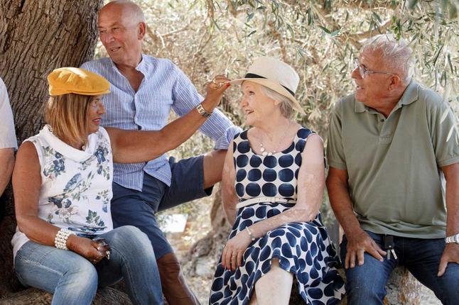 Photo of four people in summery clothes in a park