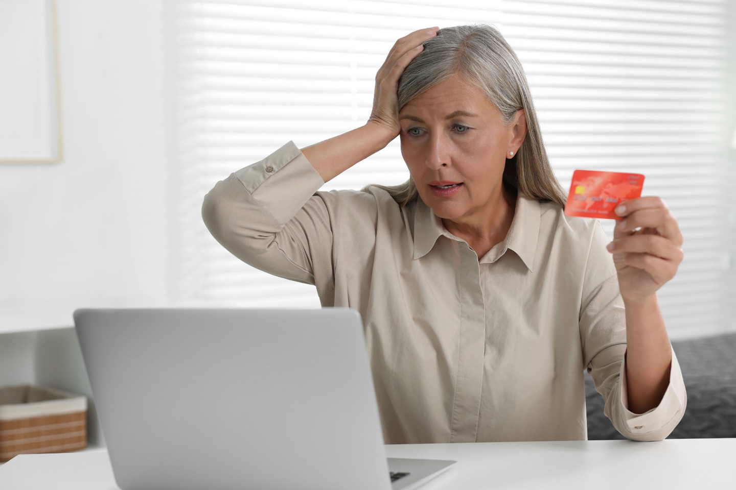 Photo of woman holding credit card sitting at a laptop