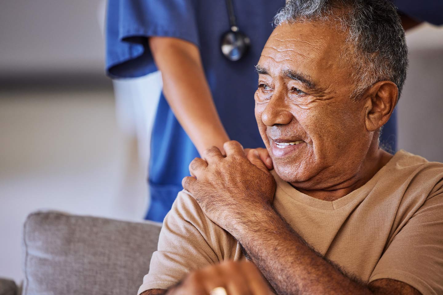 Photo of seated older man with a nurse behind him