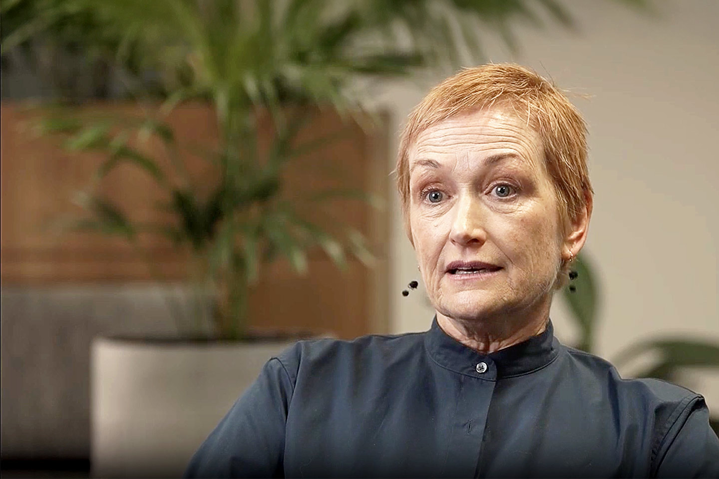 Photo of a woman with a ginger pixie cut and black shirt