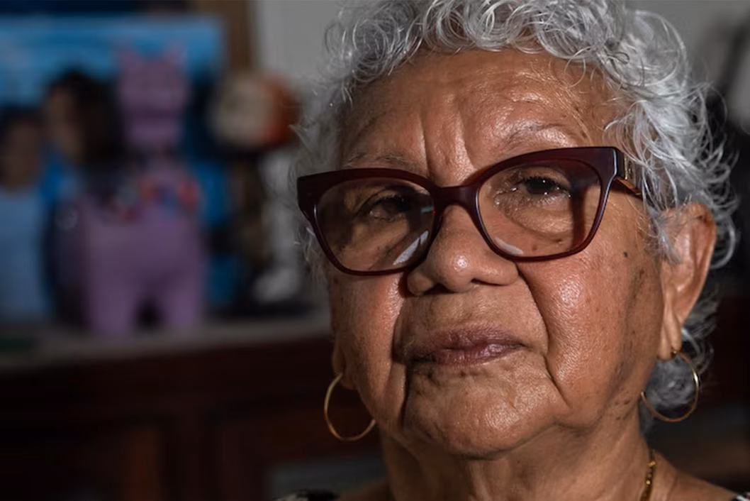 Photo of a woman wearing dark red glasses and gold hoops