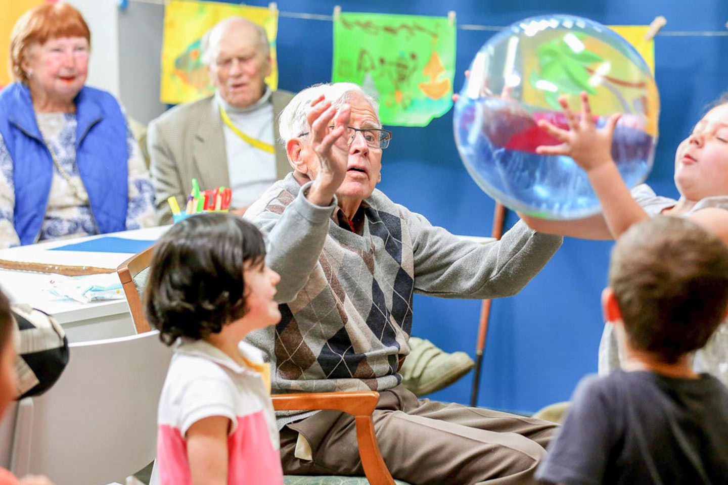 Image of an older man and primary children interacting at school