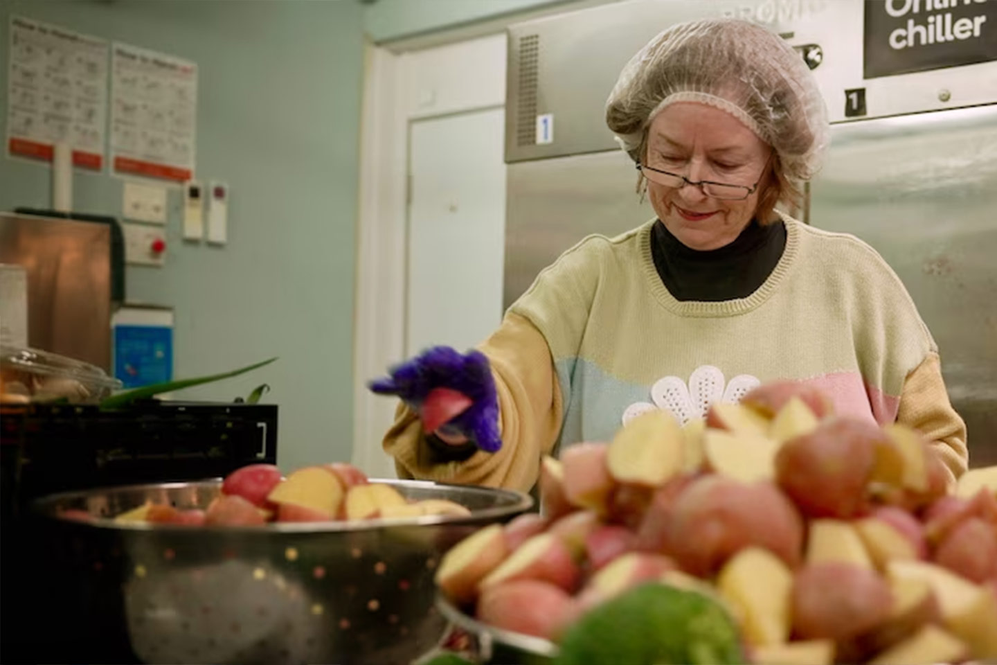 Photo of a woman prepping potatoes in a commercial kitchen