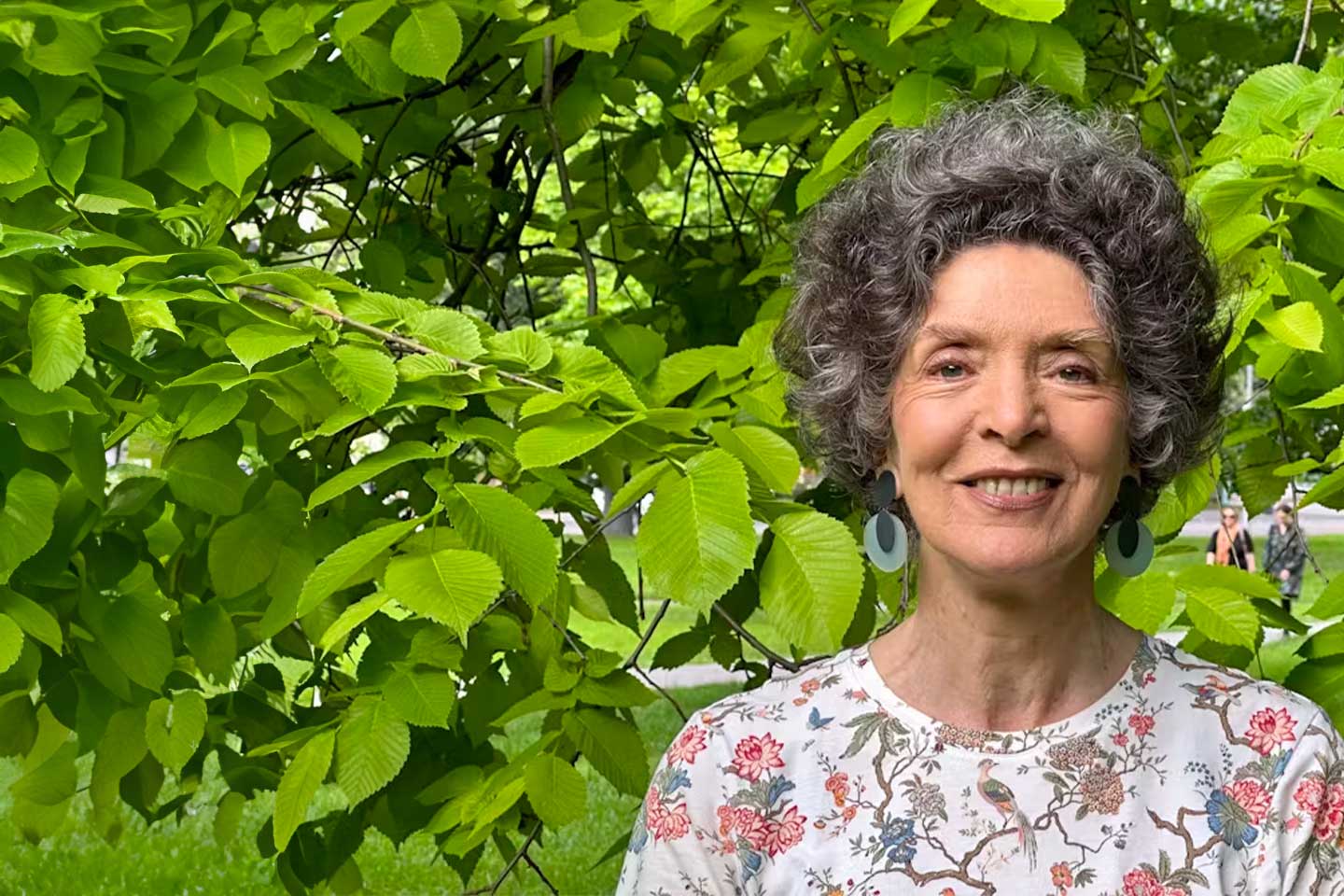 Photo of woman standing in front of lush greenery