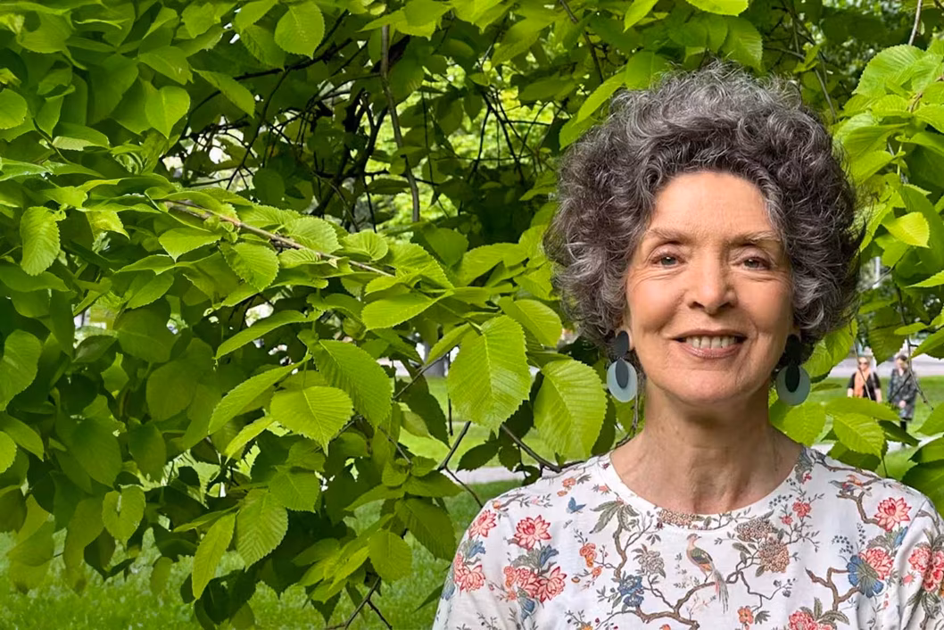 Photo of woman standing in front of lush greenery