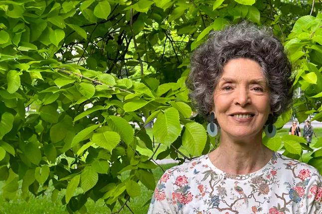 Photo of woman standing in front of lush greenery