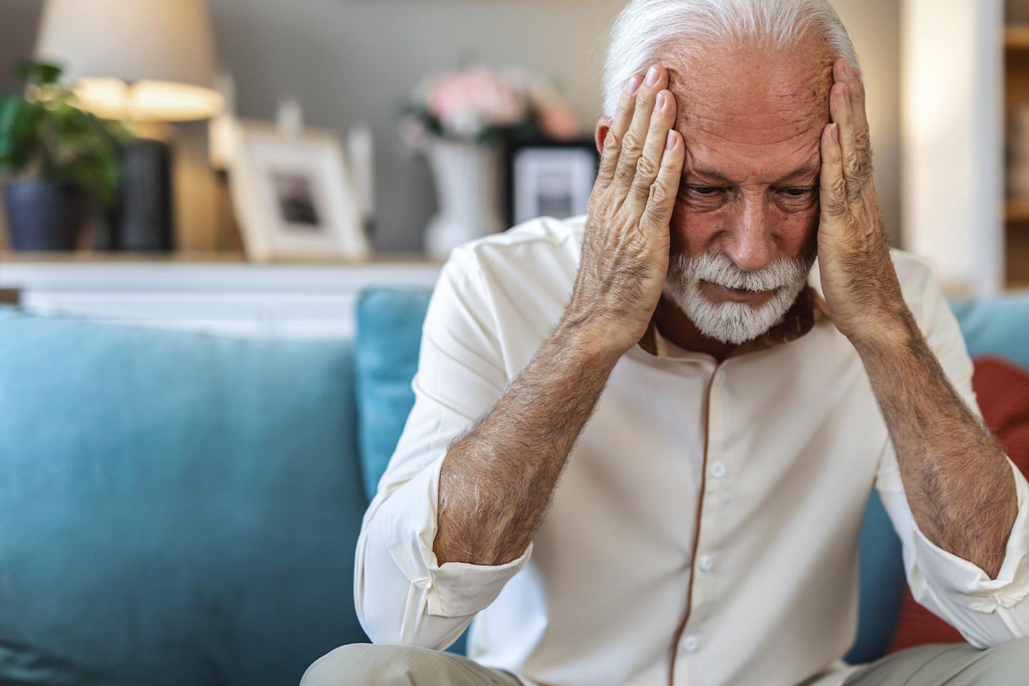 Photo of man on a blue couch with his head in his hands