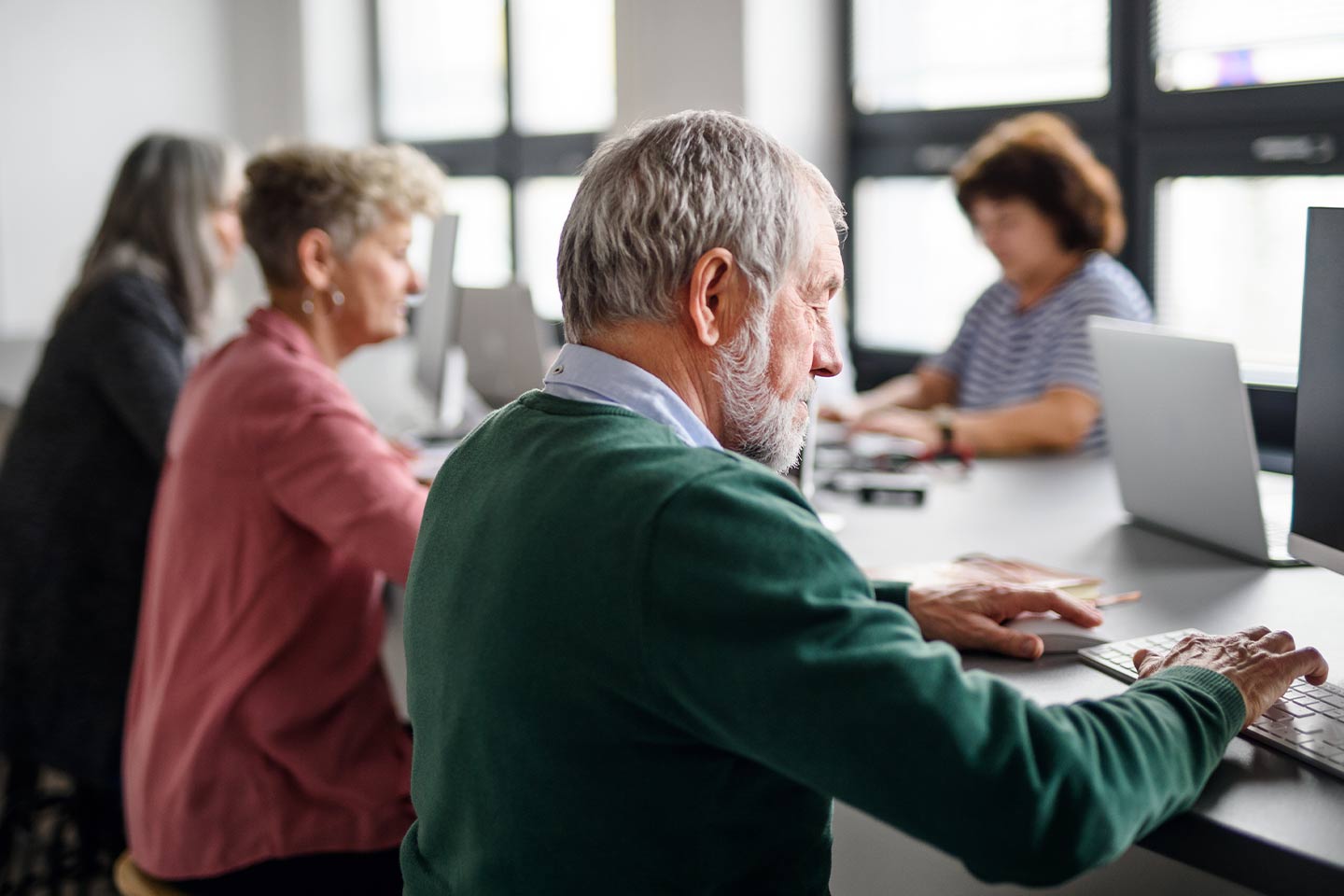 Photo of computer users of various ages in a light filled space