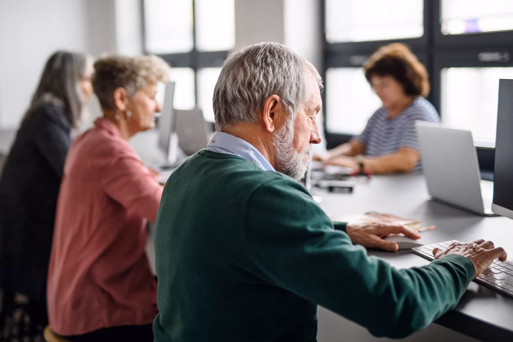 Photo of computer users of various ages in a light filled space
