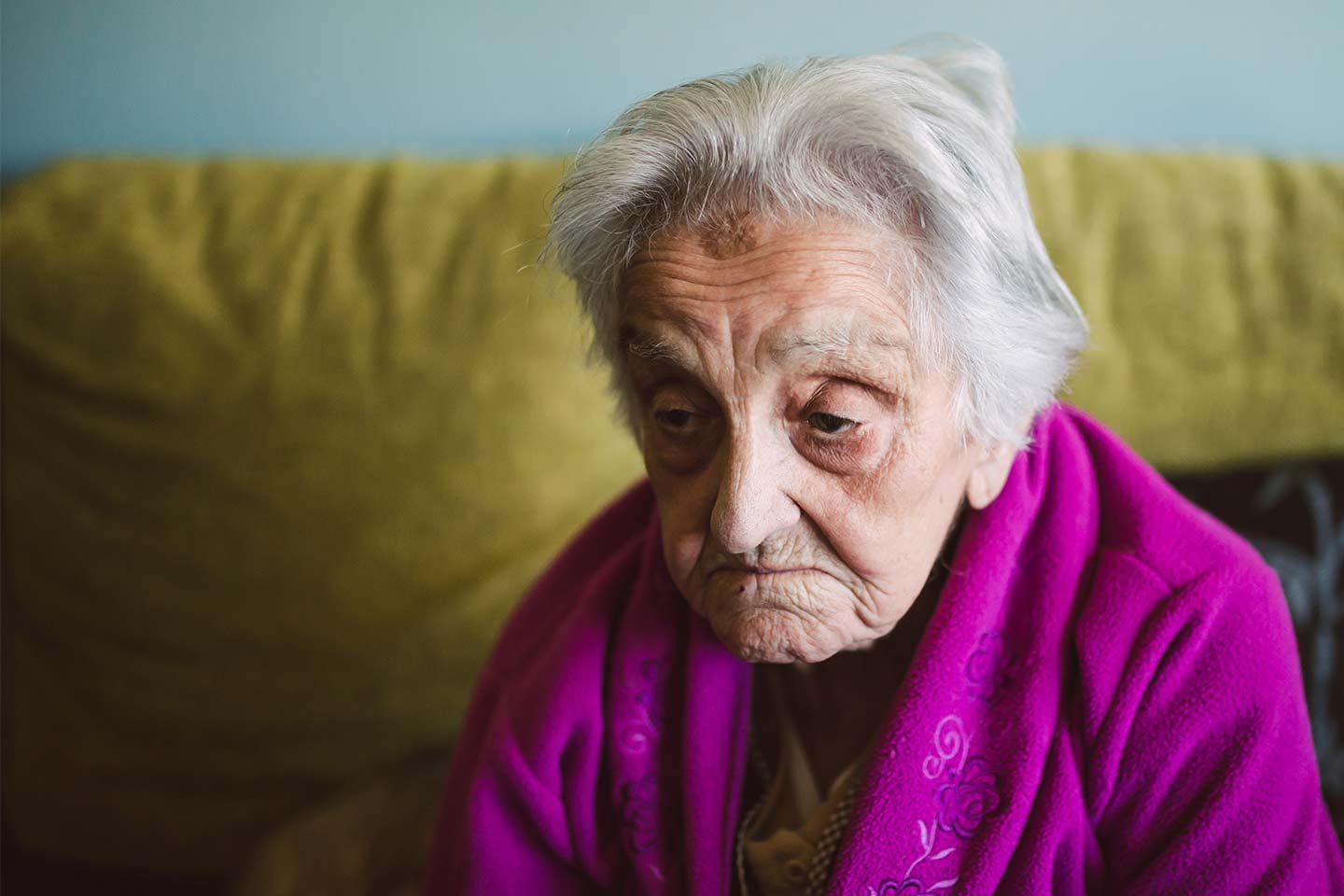 Photo of a glum older lady in a magenta dressing gown