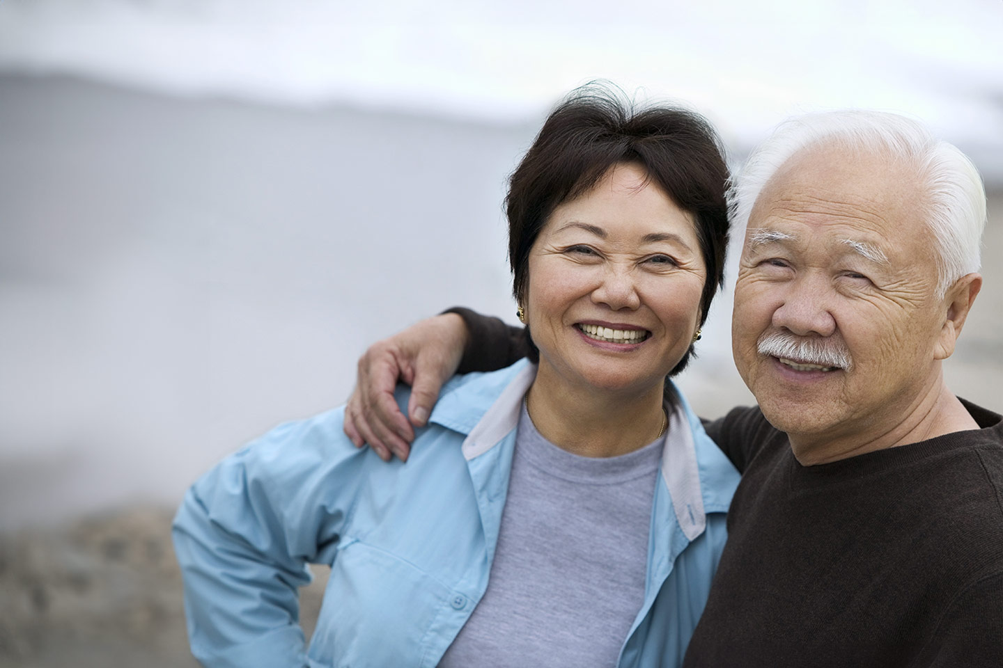 Image of an older Asian husband and wife outside near a beach
