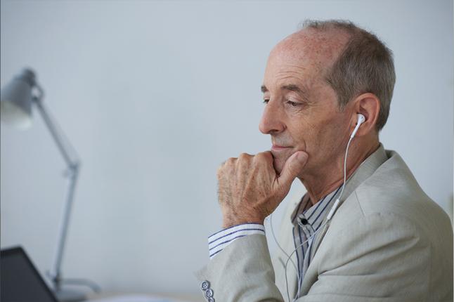 Photo of man in a suit wearing white earbuds