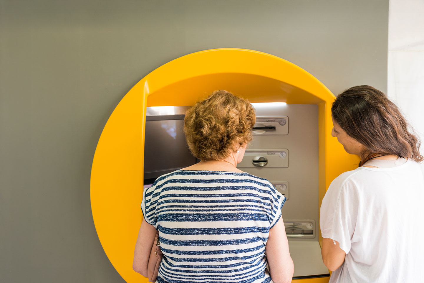 Mother and adult daughter at an ATM machine