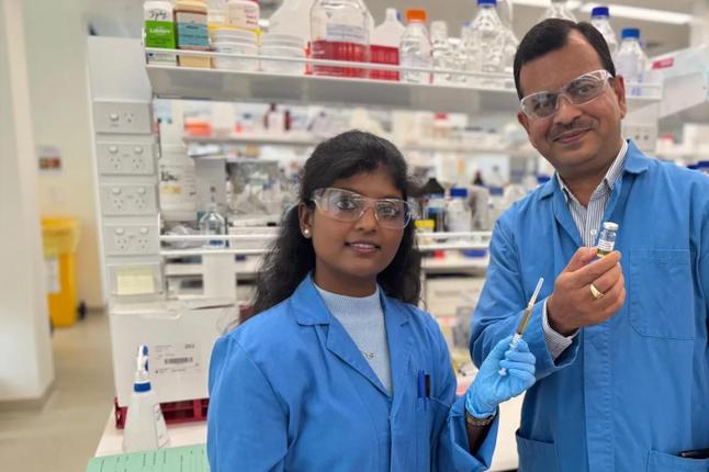 Photo of two scientists in blue coats in a lab