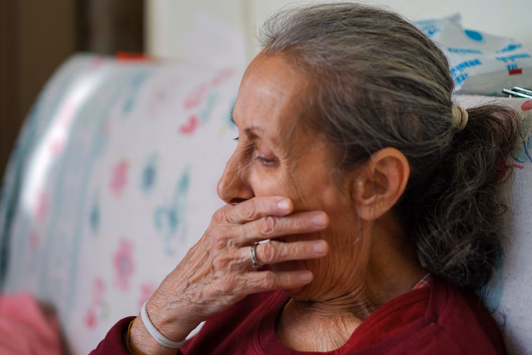 Photo of woman in a burgundy top with her hand over her mouth