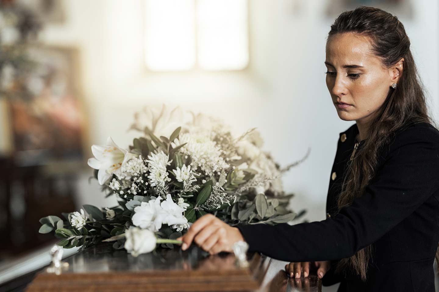 Photo of a woman placing a white rose on a coffin
