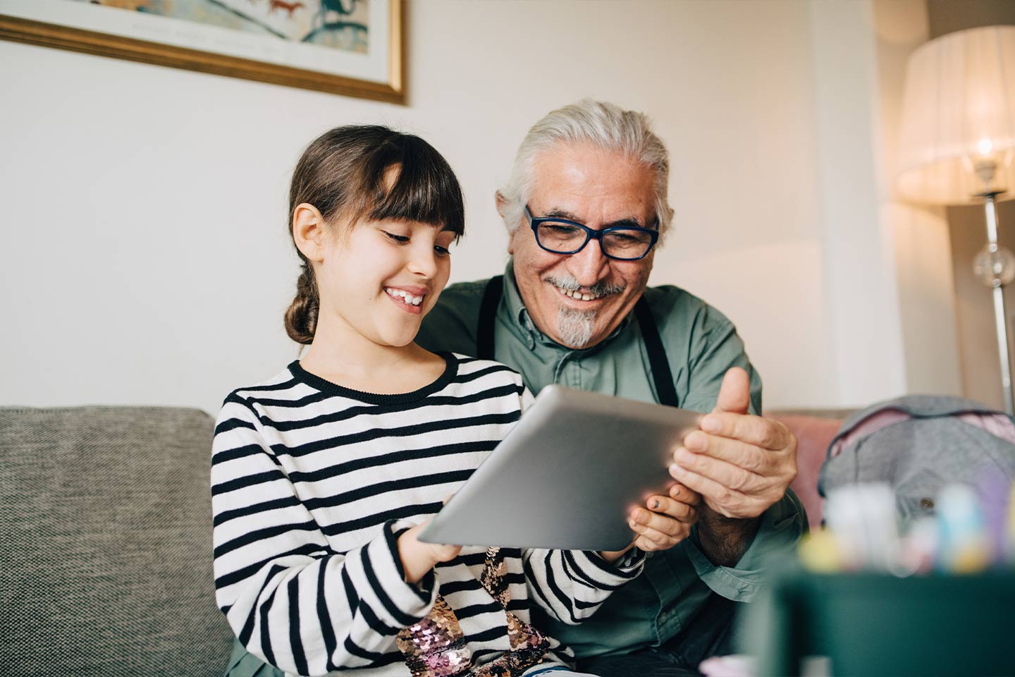 Photo of girl and man looking at a tablet and smiling
