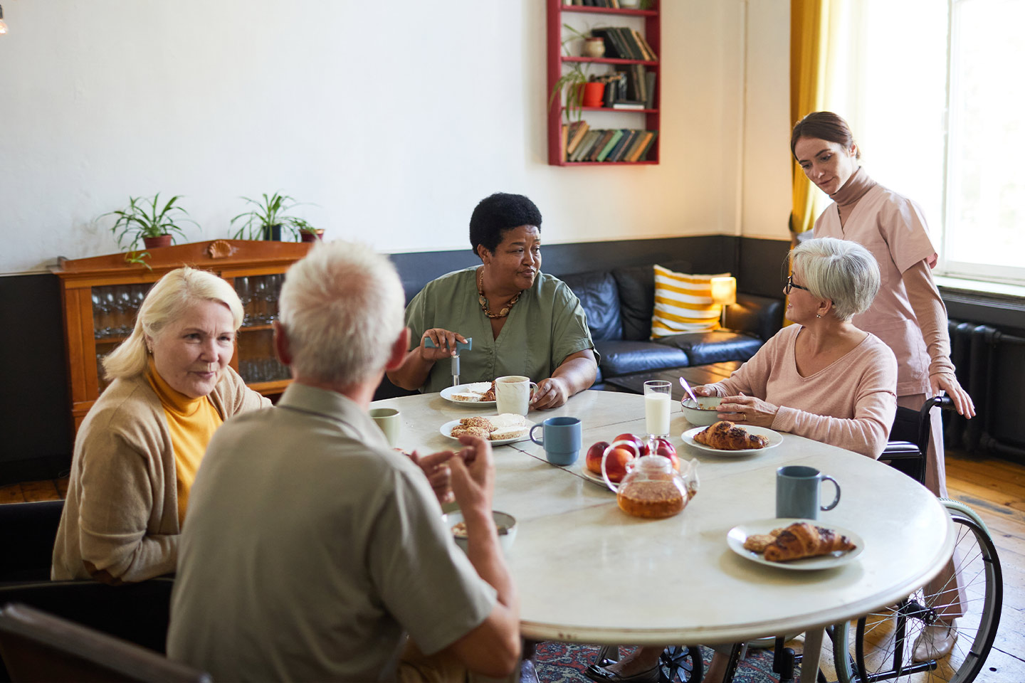 Photo of a group of people having tea and croissants round a table