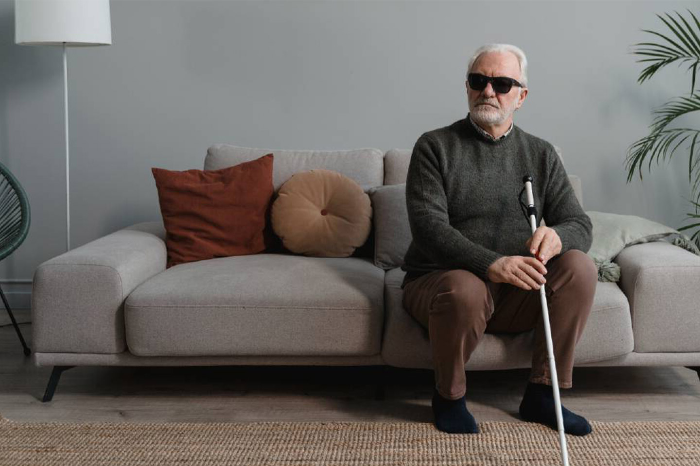 Photo of a man wearing black glasses and holding a white cane