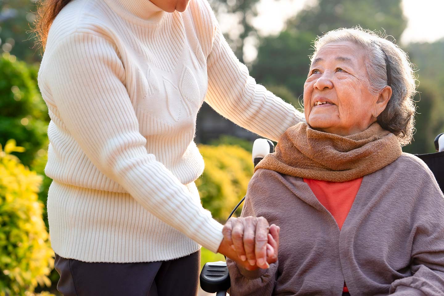 Photo of a woman in a wheelchair looking up at her helper