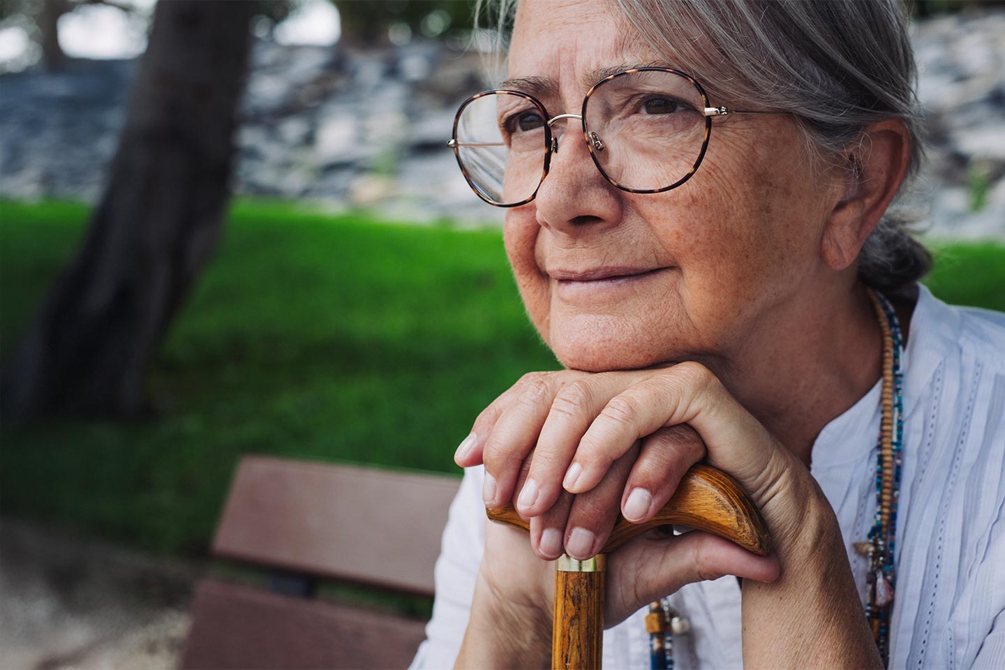Photo of a woman wearing beads sitting on a park bench