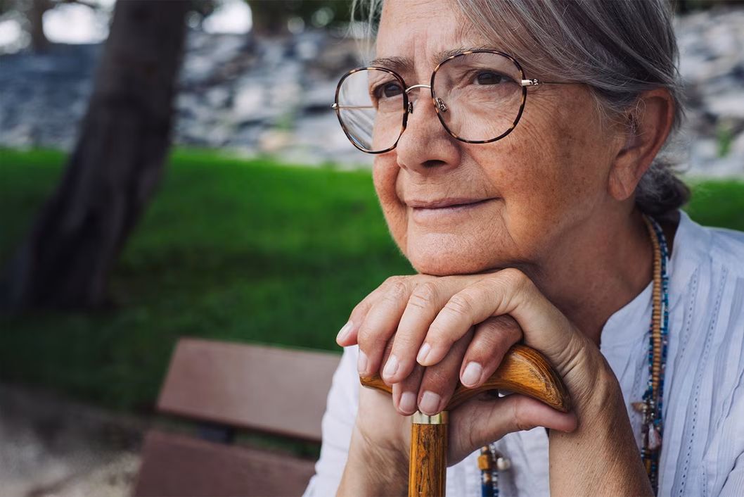 Photo of a woman wearing beads sitting on a park bench