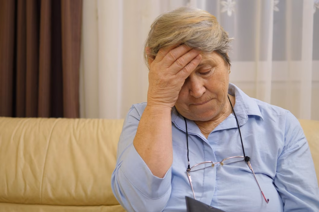 Photo of a woman in a blue shirt with her head in her hand