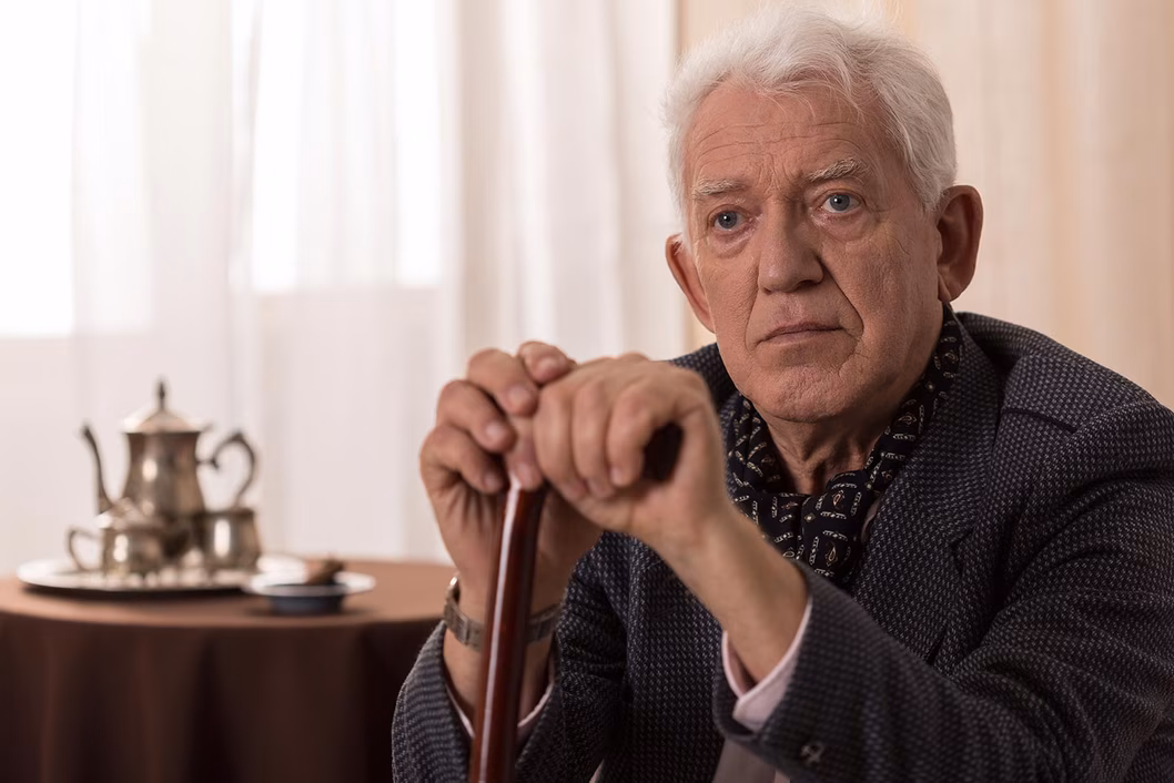 Photo of a man resting his hands on his walking stick