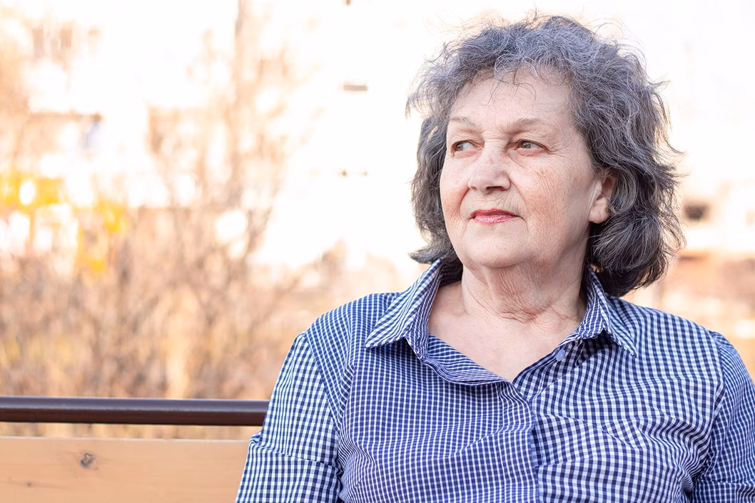 Photo of older woman in a check shirt looking sceptical