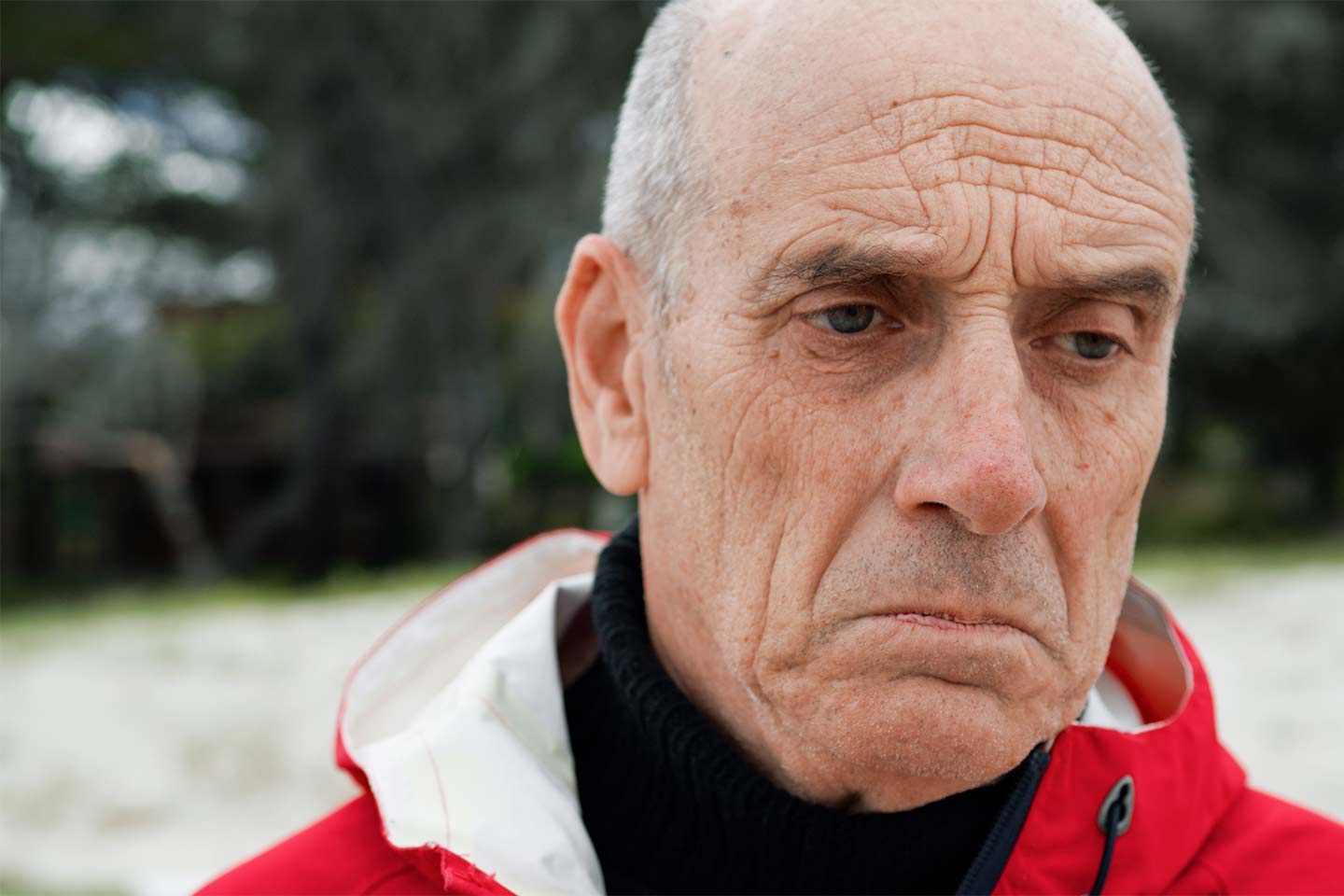 Photo of a glum man wearing a red jacket