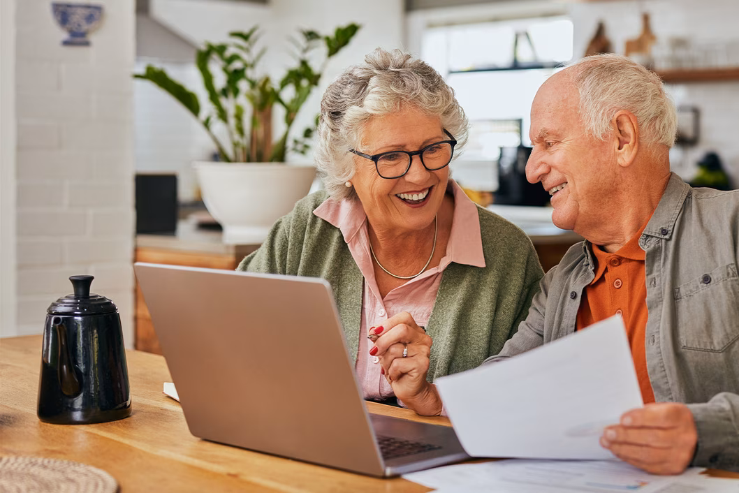 Photo of a smiling couple sitting at their laptop