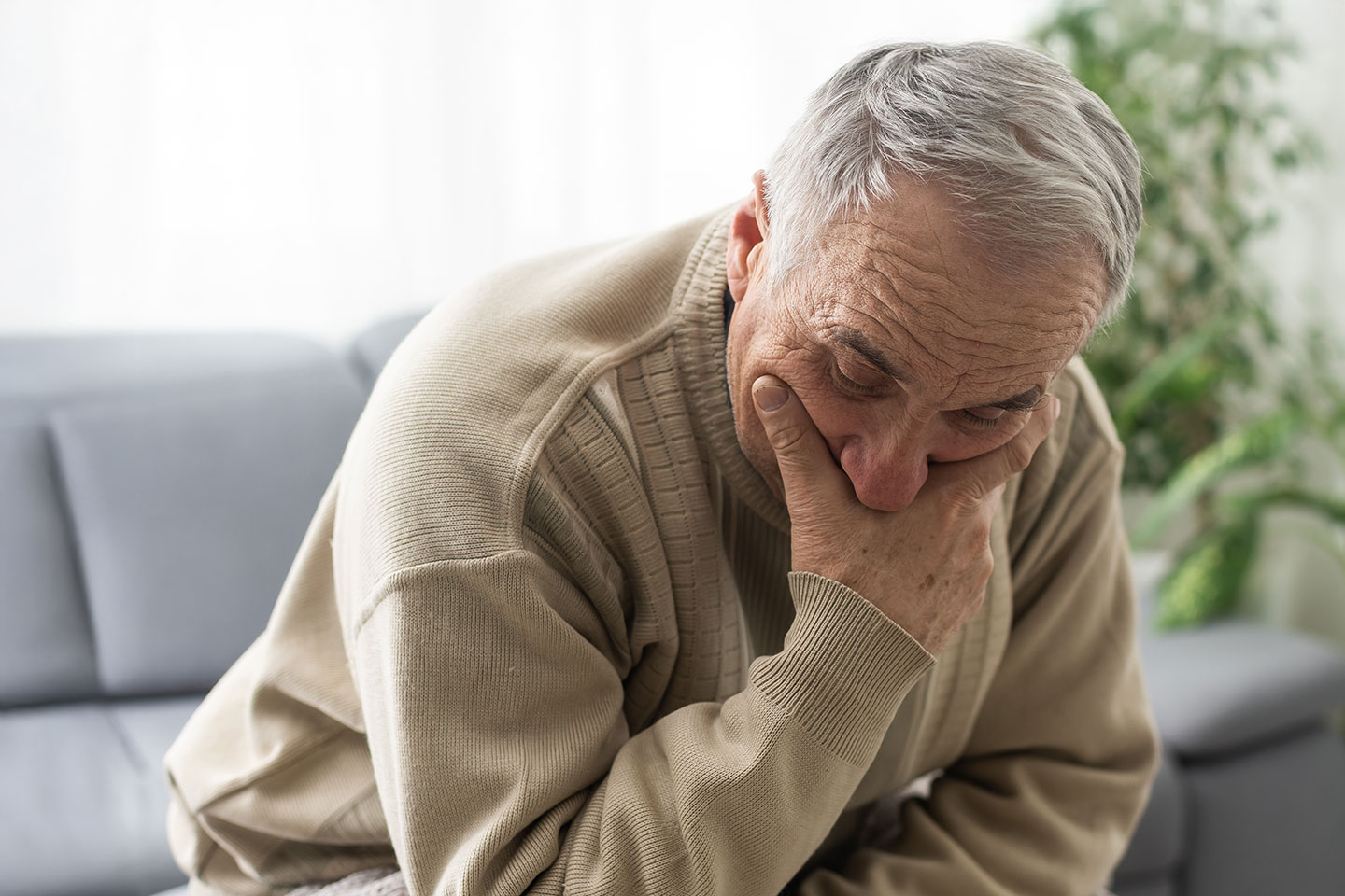 Image of an older man who is sad and leaning forward and looking down