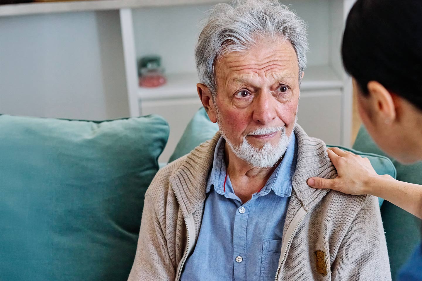 Photo of a health worker's hand on a man's shoulder