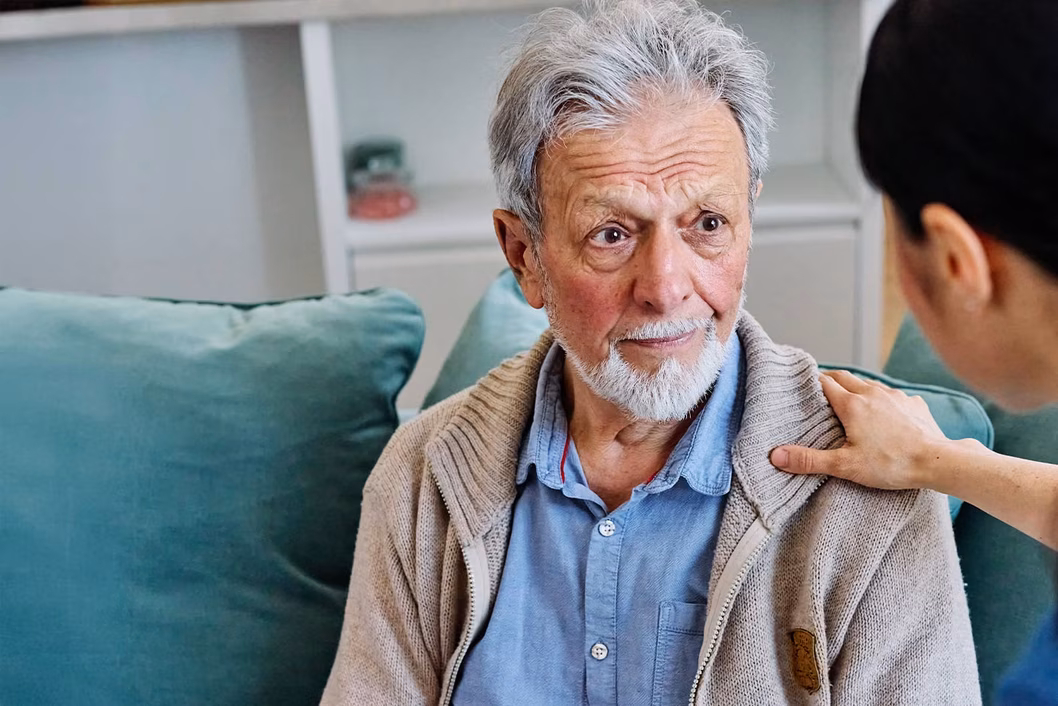 Photo of a health worker's hand on a man's shoulder