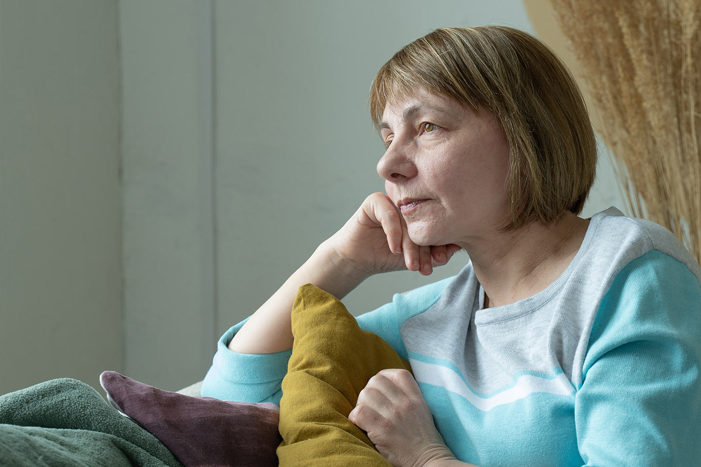 Photo of a woman amongst cushions resting her chin on her hand