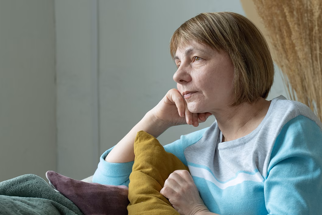 Photo of a woman amongst cushions resting her chin on her hand