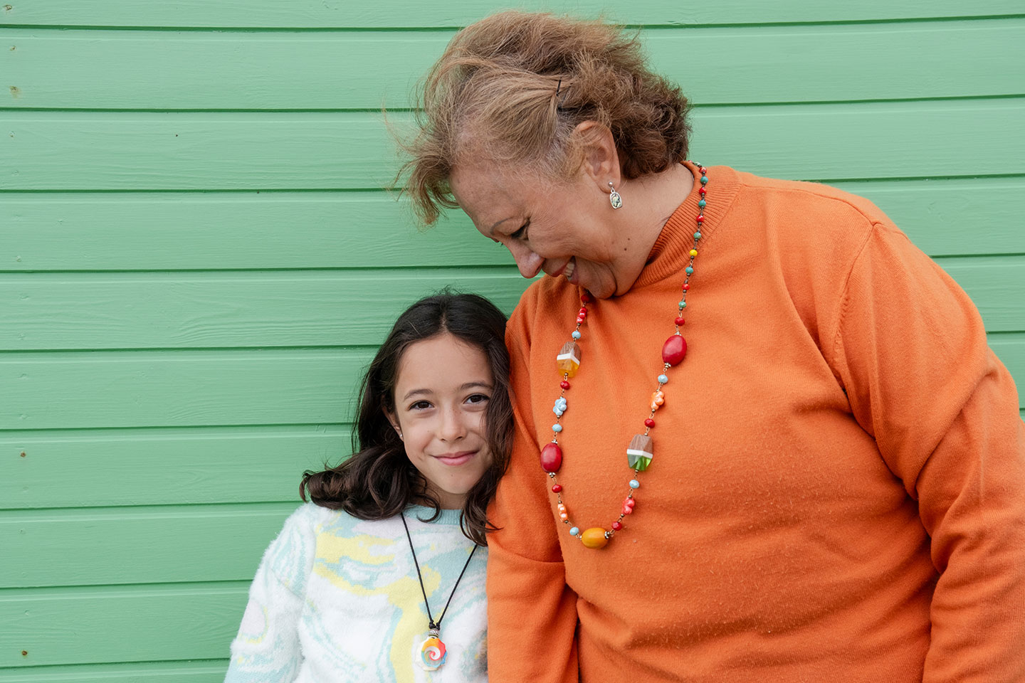 Photo of a woman and child standing against a green wall