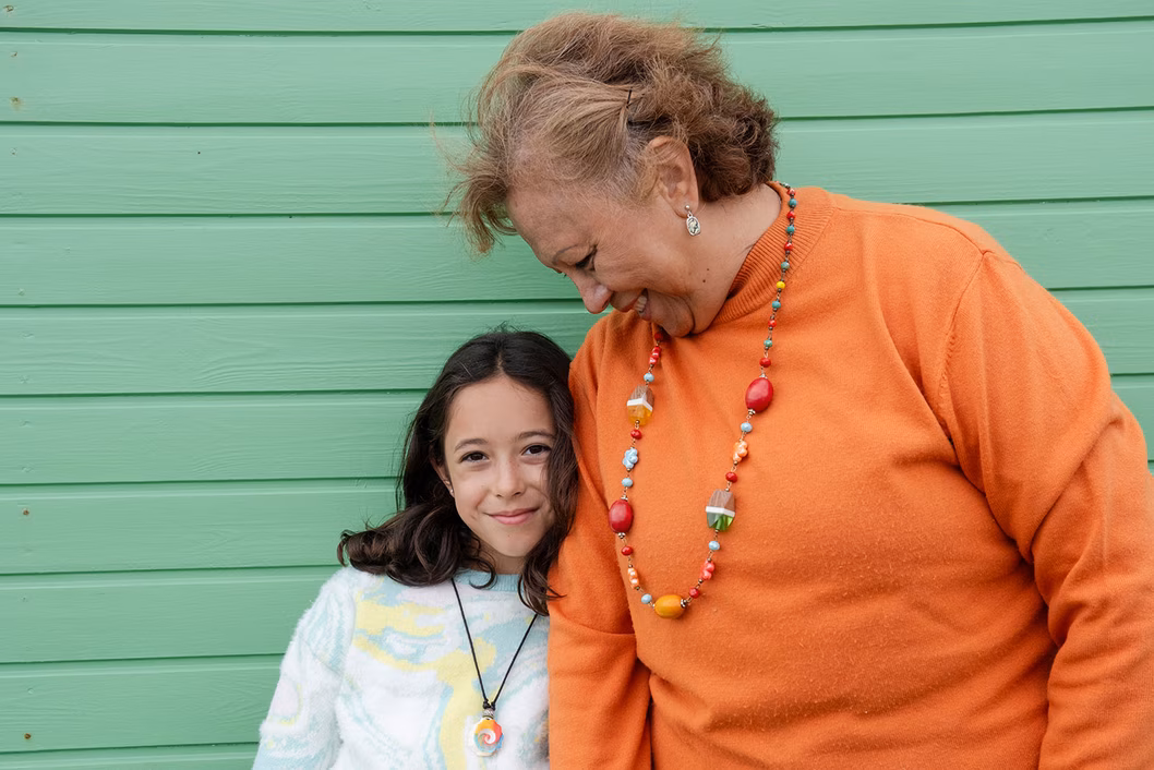Photo of a woman and child standing against a green wall