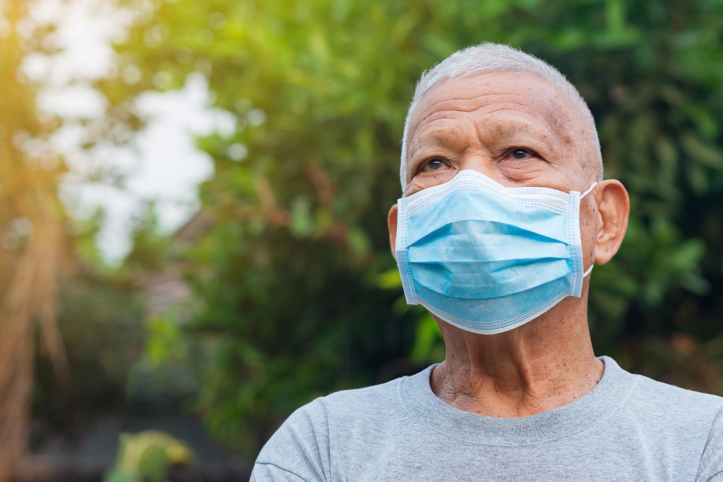 Photo of a man outdoors wearing a blue face mask