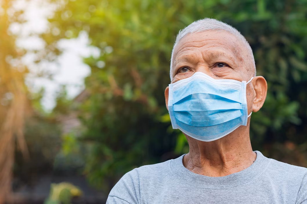 Photo of a man outdoors wearing a blue face mask