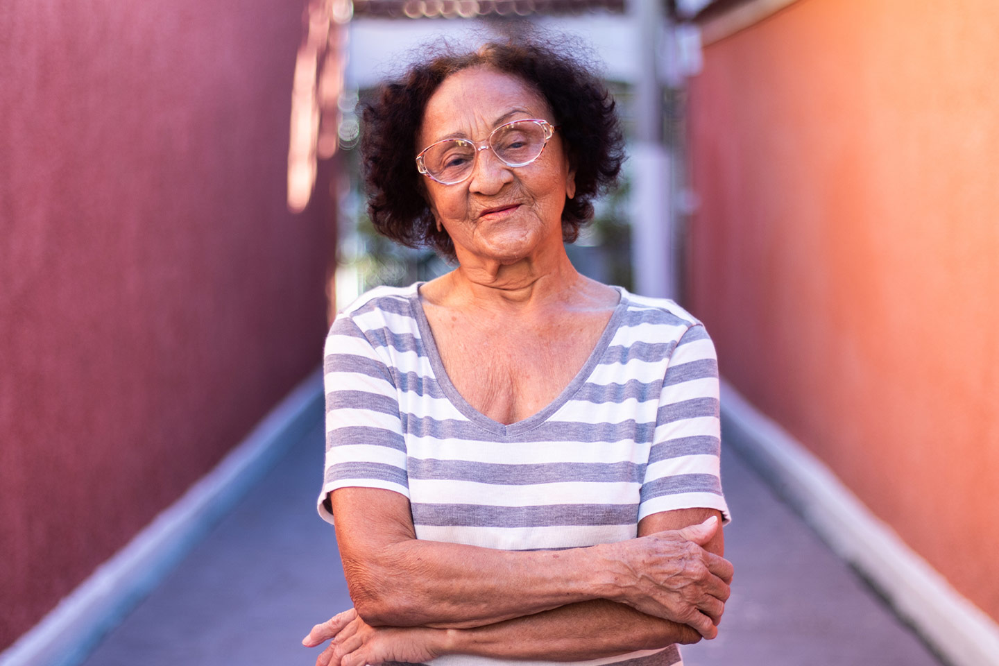 Image of an older woman who is wearing a white and grey striped t-shirt