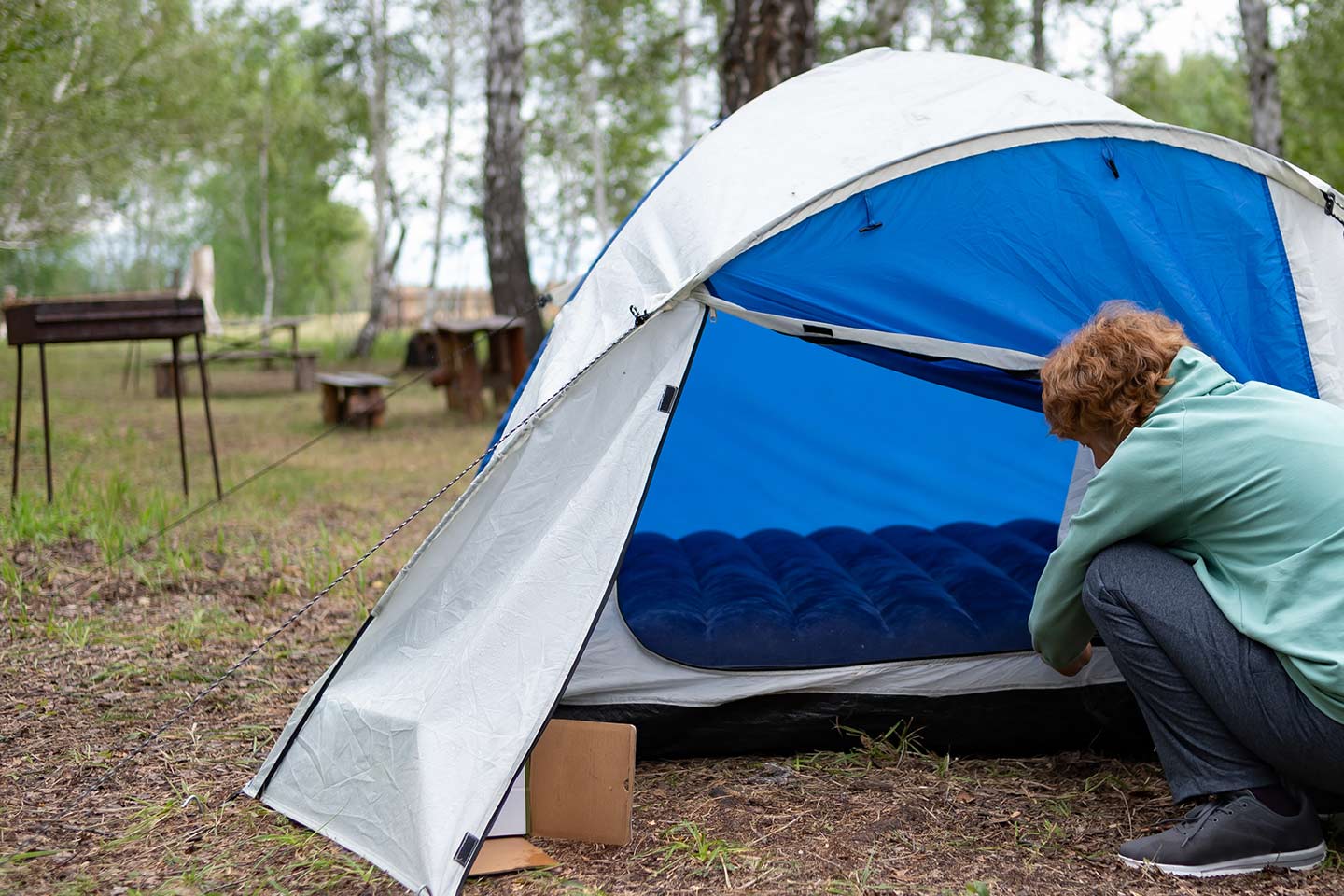Photo of a person hunkered down in front of a blue tent