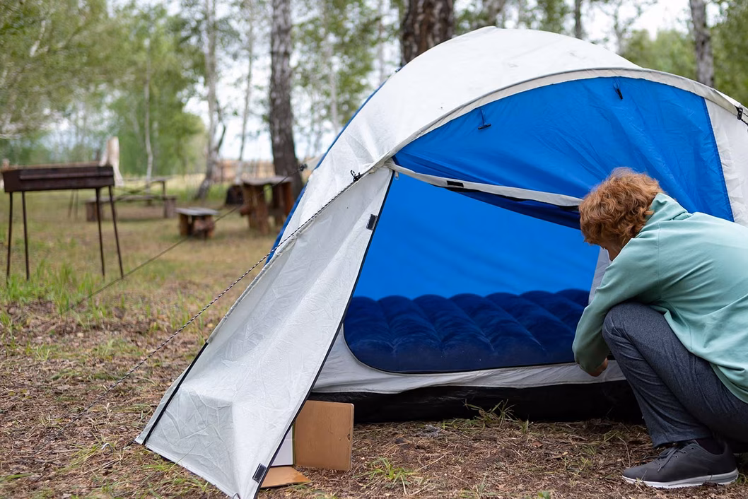 Photo of a person hunkered down in front of a blue tent