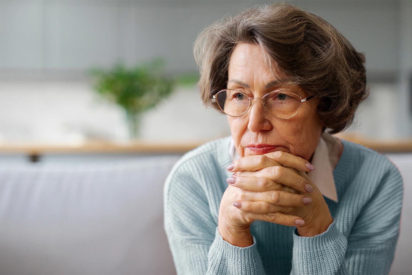 Photo of a pensive woman with her chin resting on clasped hands