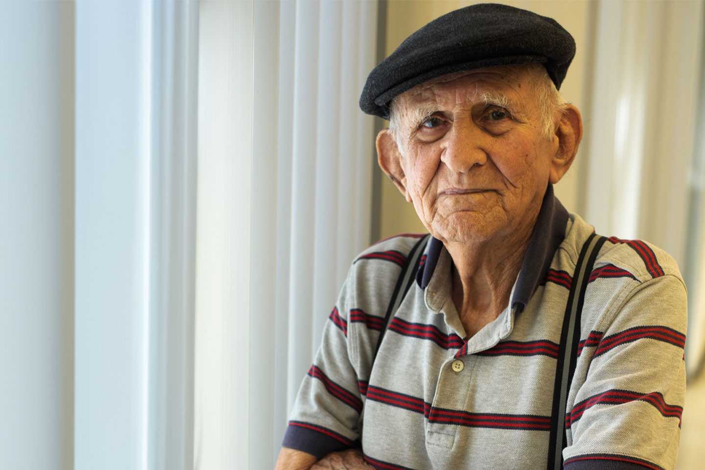 Older man in a stripped polo shirt and wearing a cap