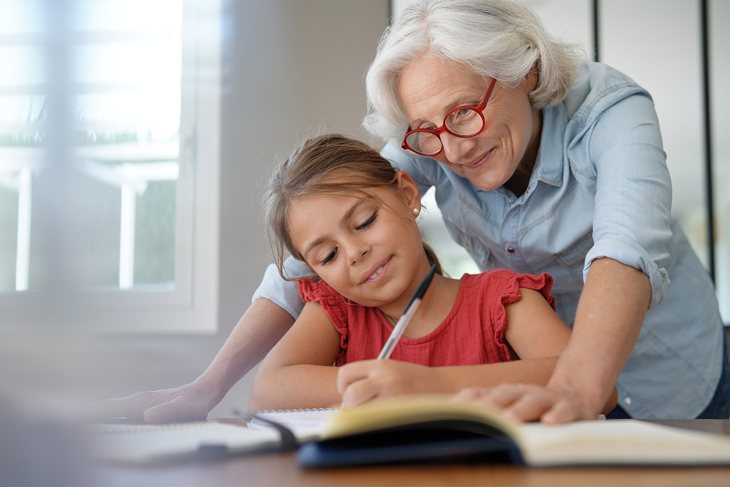 Photo of a grandmother helping a young girl with her homework