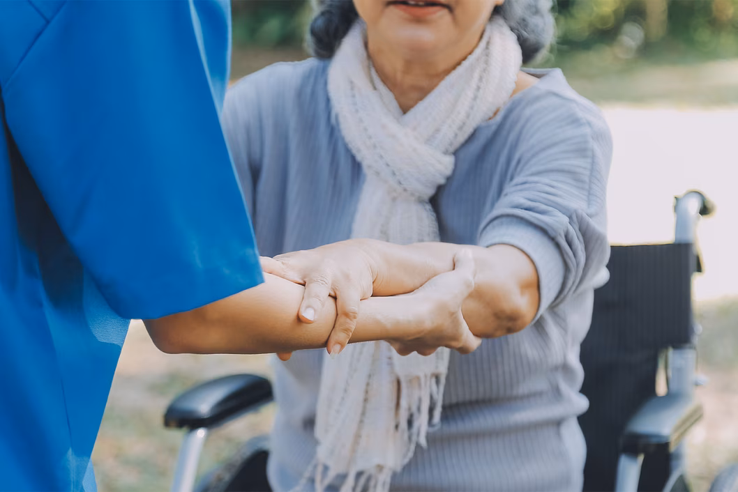 Photo of a woman being helped out of her wheelchair